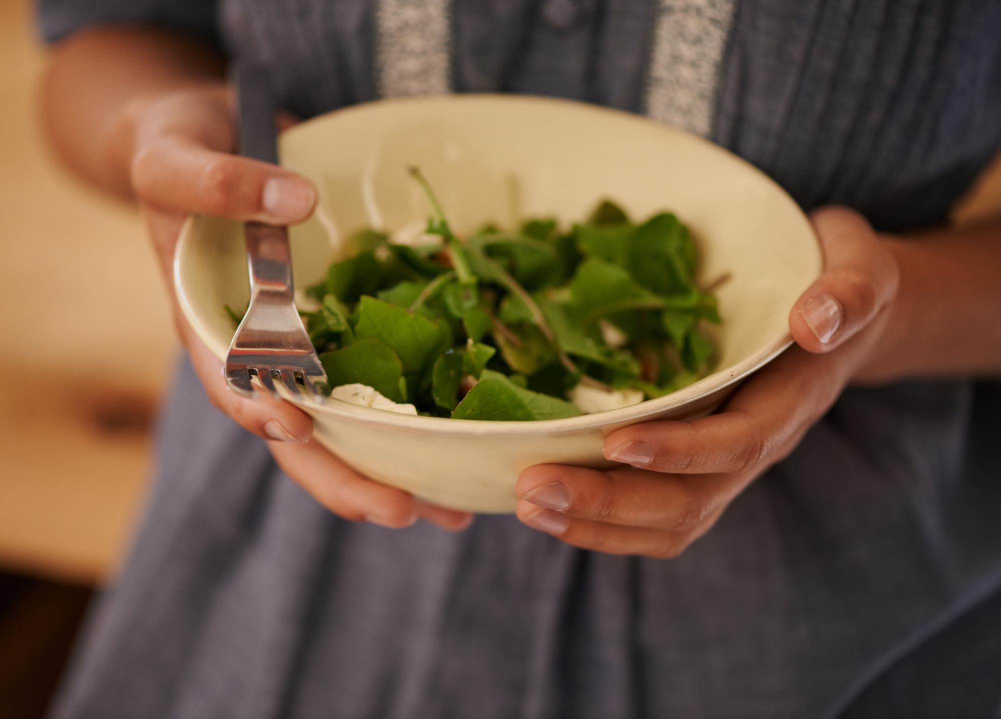 Close-up of hands arranging herbs on a plated dish